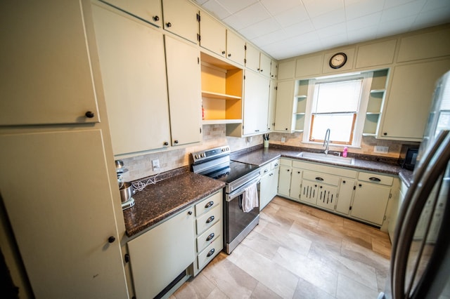kitchen featuring open shelves, cream cabinets, stainless steel appliances, and a sink