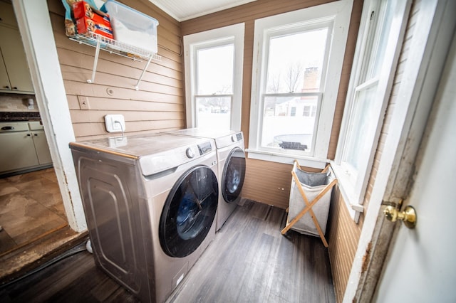 laundry room featuring wooden walls, wood finished floors, washing machine and clothes dryer, and laundry area