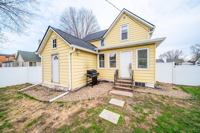 rear view of property featuring a fenced backyard, an outdoor structure, roof with shingles, and entry steps