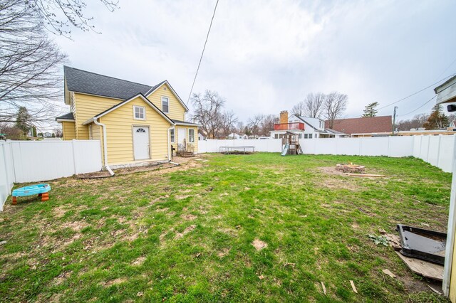 view of yard with a fenced backyard, an outdoor fire pit, and a playground