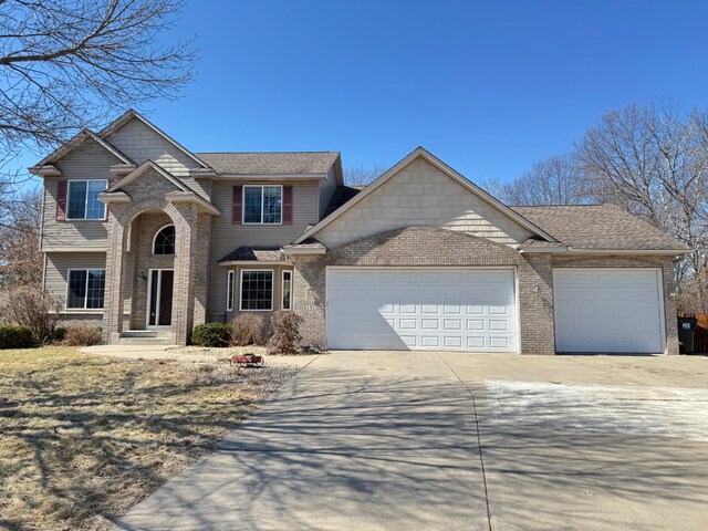traditional-style home with a garage, brick siding, and driveway