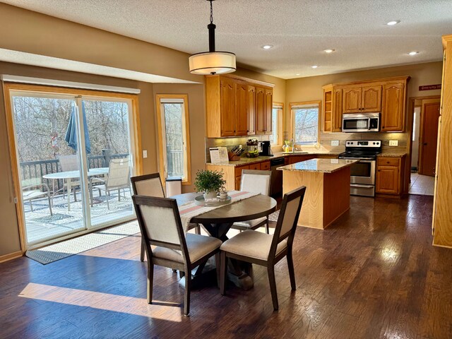 kitchen with tasteful backsplash, a sink, appliances with stainless steel finishes, dark wood-style floors, and a center island