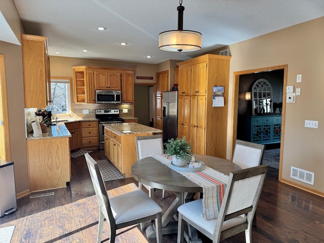kitchen featuring baseboards, visible vents, appliances with stainless steel finishes, and a kitchen island