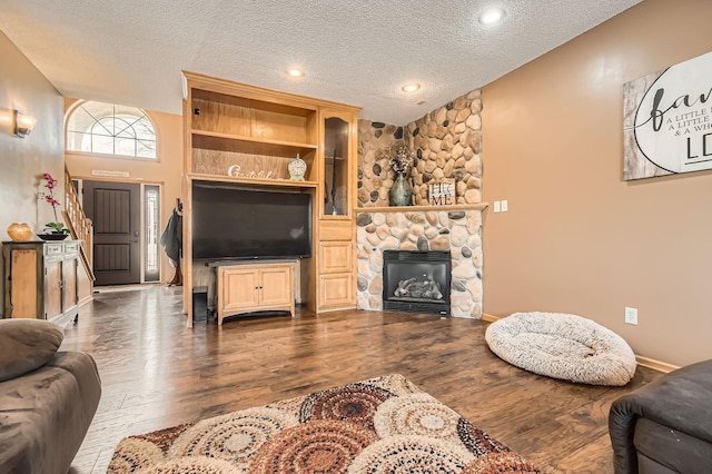 living area with a fireplace, a textured ceiling, dark wood finished floors, and baseboards