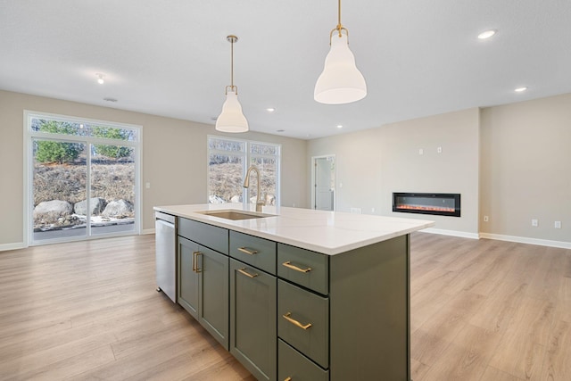 kitchen with a sink, stainless steel dishwasher, a center island with sink, hanging light fixtures, and light wood-style floors
