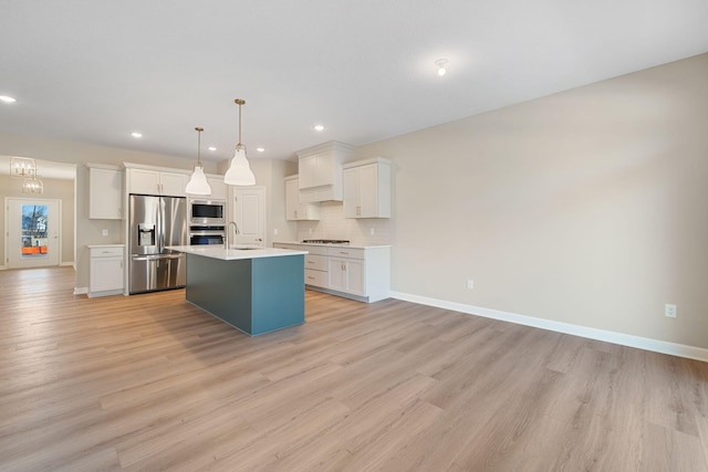 kitchen with light countertops, backsplash, white cabinetry, light wood-style flooring, and stainless steel appliances