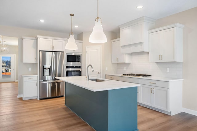 kitchen with light countertops, tasteful backsplash, light wood-type flooring, stainless steel appliances, and a sink