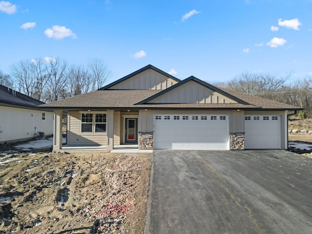 single story home with driveway, stone siding, board and batten siding, a shingled roof, and a garage