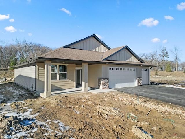 view of front of house featuring driveway, an attached garage, board and batten siding, and roof with shingles