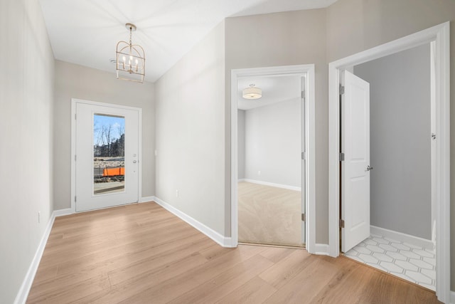 corridor with baseboards, light wood-style flooring, and an inviting chandelier