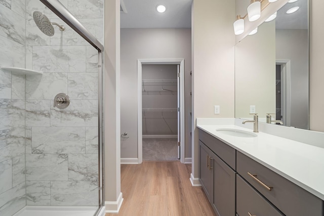 full bathroom featuring wood finished floors, a stall shower, a walk in closet, and vanity