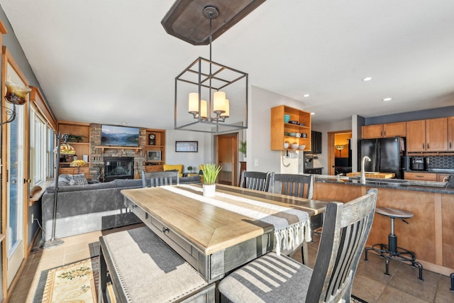 dining space with a notable chandelier, a fireplace, recessed lighting, and light tile patterned floors