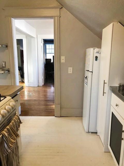 2715 Marshall St NE, Minneapolis, MN 55418 - kitchen with light wood finished floors, white cabinets, freestanding refrigerator, gas range, and lofted ceiling