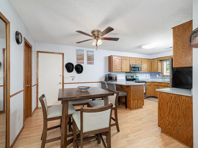 4237 Centerville Rd, Vadnais Heights, MN 55127 - kitchen featuring appliances with stainless steel finishes, a textured ceiling, light wood-style floors, a peninsula, and brown cabinets