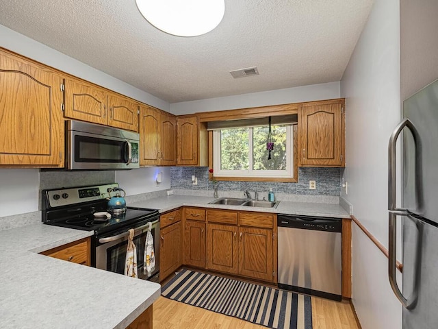4237 Centerville Rd, Vadnais Heights, MN 55127 - kitchen with stainless steel appliances, a sink, light countertops, brown cabinets, and a textured ceiling