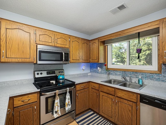 4237 Centerville Rd, Vadnais Heights, MN 55127 - kitchen with appliances with stainless steel finishes, a sink, light countertops, a textured ceiling, and brown cabinetry