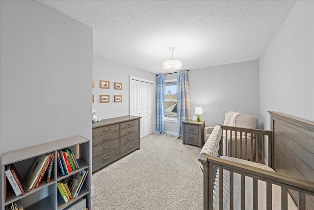 bedroom with a closet, a textured ceiling, and light colored carpet