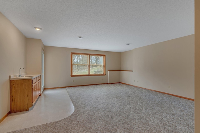 12114 260th St, Saint Cloud, MN 56301 - unfurnished living room with light colored carpet, baseboards, a textured ceiling, and bar with sink