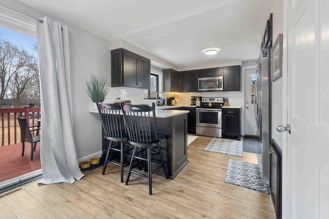 16137 Ahrens Hill Rd, Brainerd, MN 56401 - kitchen with appliances with stainless steel finishes, light wood-style flooring, a peninsula, light countertops, and a sink