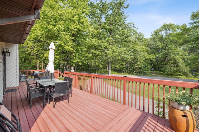 16137 Ahrens Hill Rd, Brainerd, MN 56401 - wooden deck featuring outdoor dining area, a lawn, and view of wooded area