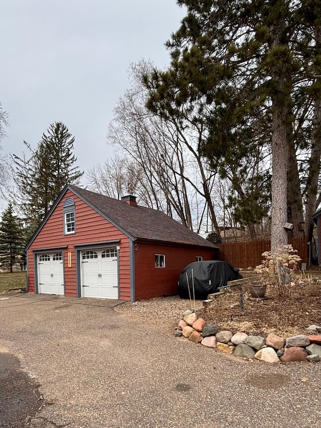 709 Riverside Dr N, North Hudson, WI 54016 - view of side of home featuring a chimney, fence, an outdoor structure, a garage, and roof with shingles