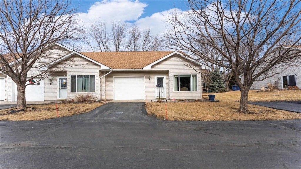 single story home with an attached garage and aphalt driveway