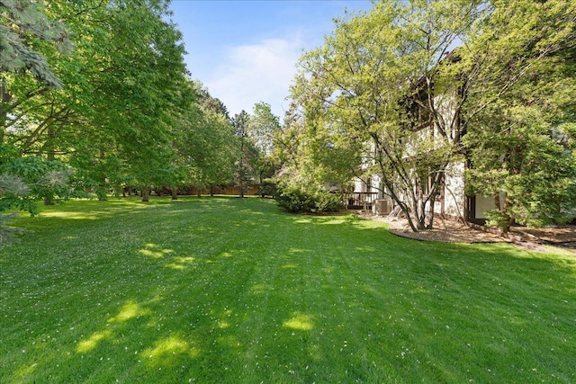 1317 Waterford Rd, Woodbury, MN 55125 - view of grassy yard featuring a wooden deck and central air condition unit