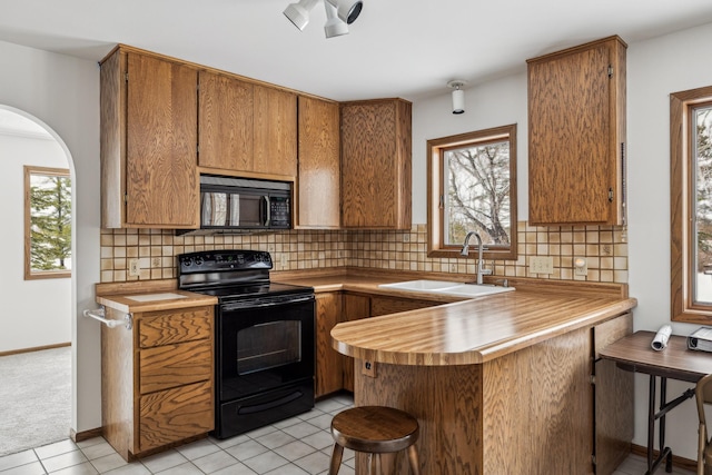 93 County 49 NW, Pine River, MN 56474 - kitchen with black appliances, a sink, a kitchen breakfast bar, a peninsula, and brown cabinetry