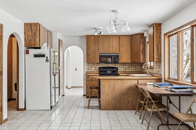 93 County 49 NW, Pine River, MN 56474 - kitchen featuring black appliances, a sink, arched walkways, brown cabinets, and decorative backsplash
