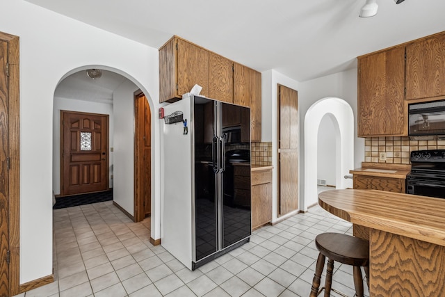 93 County 49 NW, Pine River, MN 56474 - kitchen featuring black appliances, tasteful backsplash, arched walkways, light tile patterned floors, and brown cabinetry