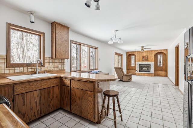 93 County 49 NW, Pine River, MN 56474 - kitchen featuring a sink, a peninsula, a glass covered fireplace, light tile patterned floors, and tasteful backsplash