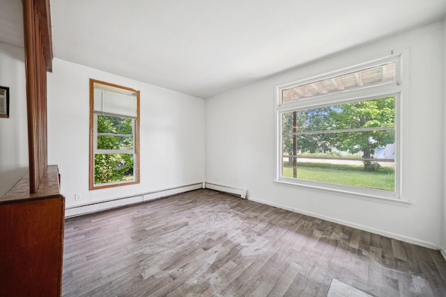 empty room featuring a baseboard radiator, baseboards, and wood finished floors