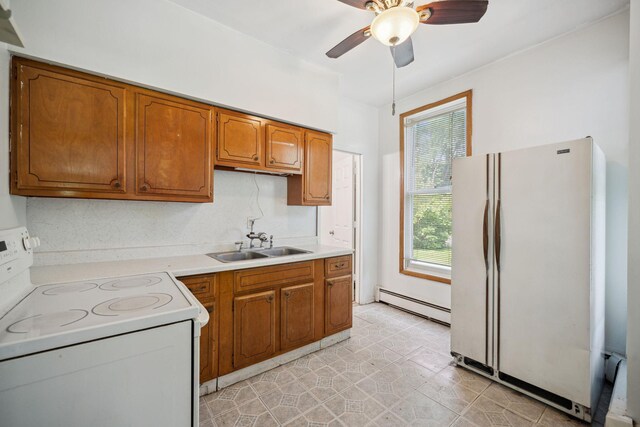 kitchen with a sink, a ceiling fan, white appliances, brown cabinetry, and a baseboard radiator