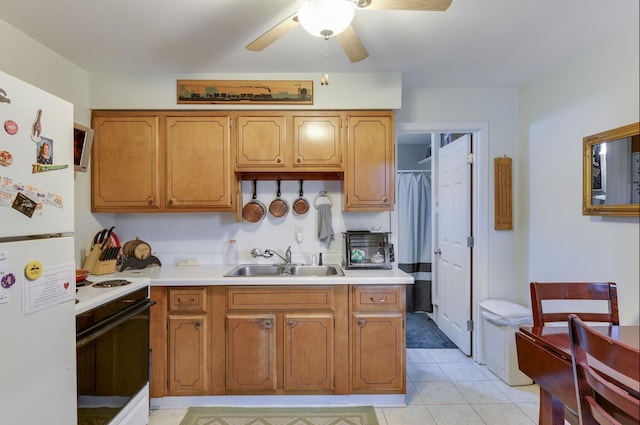 kitchen with a sink, ceiling fan, range with electric cooktop, light countertops, and freestanding refrigerator