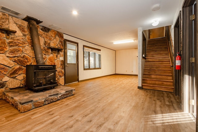 1002 11th Ave W, Alexandria, MN 56308 - unfurnished living room featuring a wood stove, wood finished floors, and stairs