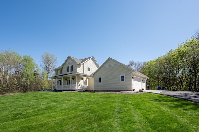 view of side of home featuring a lawn, driveway, covered porch, and an attached garage