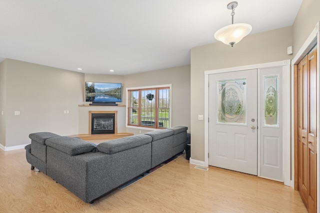 foyer entrance with recessed lighting, baseboards, a glass covered fireplace, visible vents, and light wood-type flooring