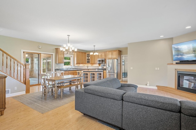 living area with baseboards, light wood-style floors, a chandelier, and recessed lighting