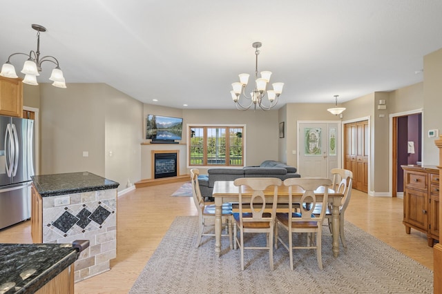 dining space with baseboards, a notable chandelier, and light wood-style flooring