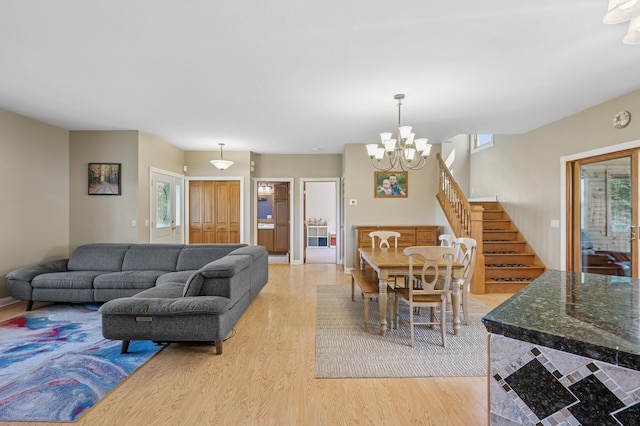 living area with a notable chandelier, light wood finished floors, and stairway