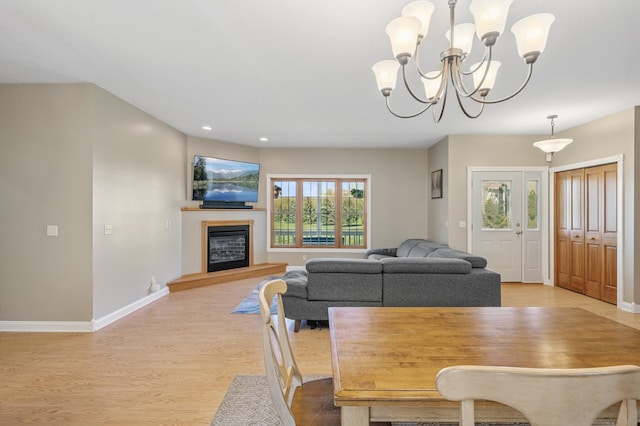 dining area with wood finished floors, recessed lighting, a chandelier, baseboards, and a glass covered fireplace