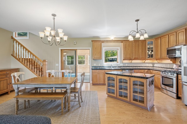 kitchen featuring pendant lighting, an inviting chandelier, appliances with stainless steel finishes, and glass insert cabinets