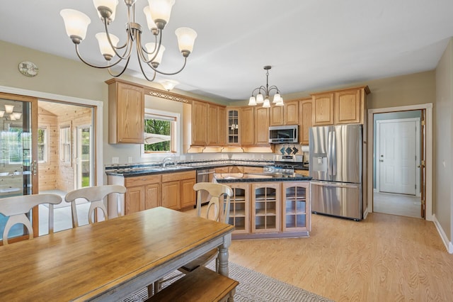 kitchen featuring glass insert cabinets, dark countertops, stainless steel appliances, light wood-type flooring, and a chandelier