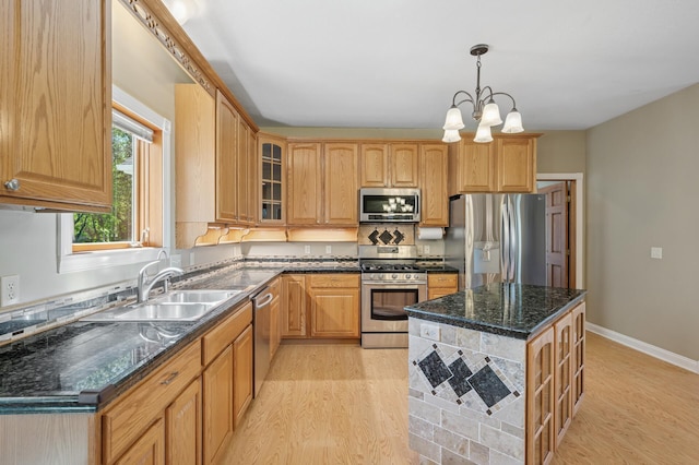 kitchen with a sink, stainless steel appliances, glass insert cabinets, and light wood-style floors