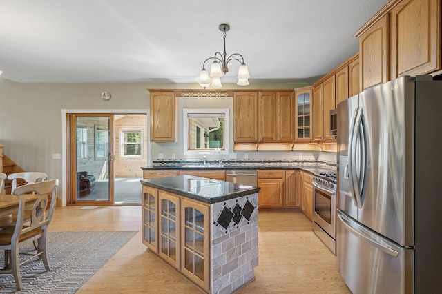 kitchen featuring a sink, a center island, glass insert cabinets, a notable chandelier, and appliances with stainless steel finishes