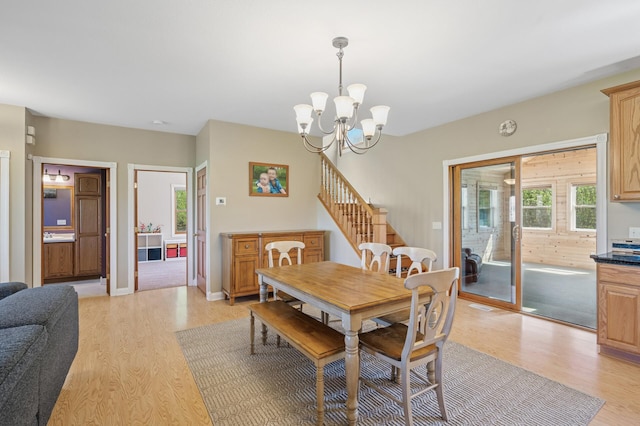 dining area with light wood-type flooring, stairway, baseboards, and a notable chandelier