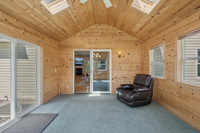 unfurnished room with carpet, wood walls, and vaulted ceiling with skylight