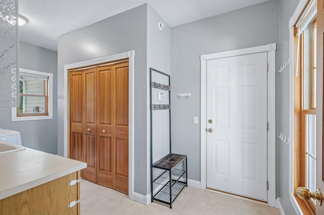 entrance foyer with light colored carpet and baseboards
