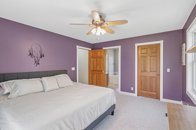 bedroom featuring baseboards, ensuite bathroom, light carpet, and a ceiling fan