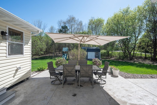 view of patio / terrace featuring a storage unit, outdoor dining space, and an outbuilding